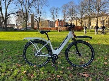 White CYCL compact family e-bike with front and rear racks in a London park