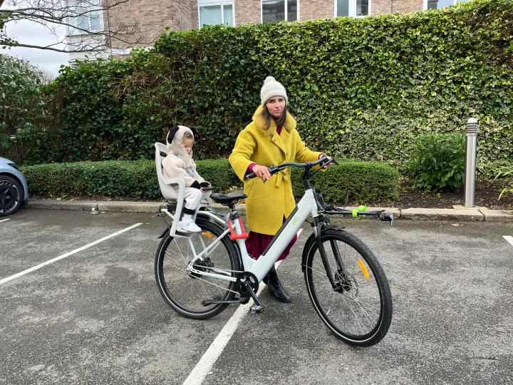 Mum standing with her electric bike, toddler settled in the rear child seat