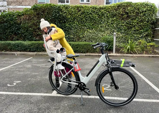 Mum settling her toddler into the child seat on a Moon Bike Rentals cargo e-bike